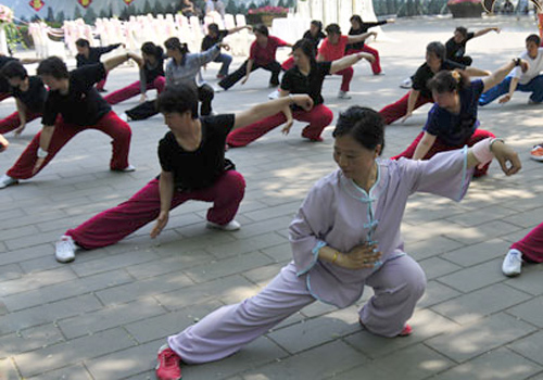 People are practicing Tai Chi at the east side of the west gate of the Park of Temple of Heaven, Beijing