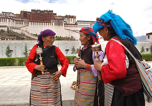 Three senior Tibetan female Buddhists are talking in front of the Potala Palace.